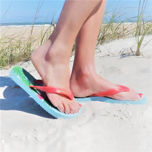 Load image into Gallery viewer, Someone's feet in flip flops on the sand.