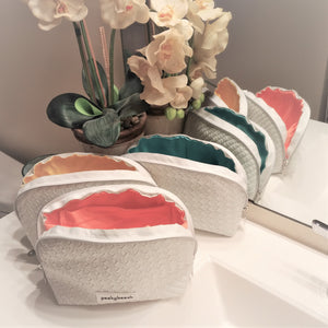 Three makeup bags in white showing the inside lining colours. Coral, Yellow and Caribbean.