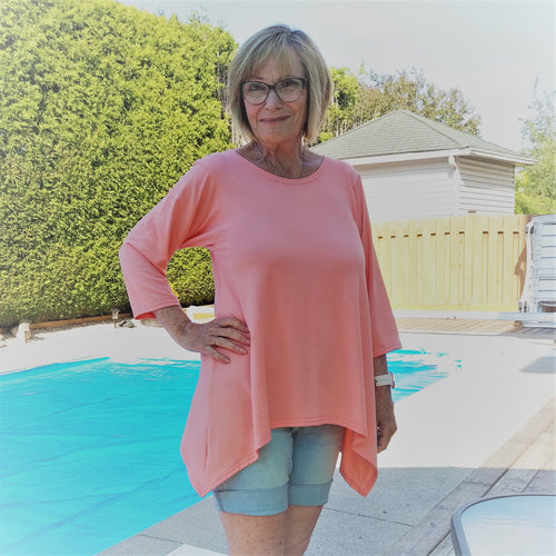 Wendy wearing a coral lounge top in her back yard. It's early spring and the cover is still on the pool.